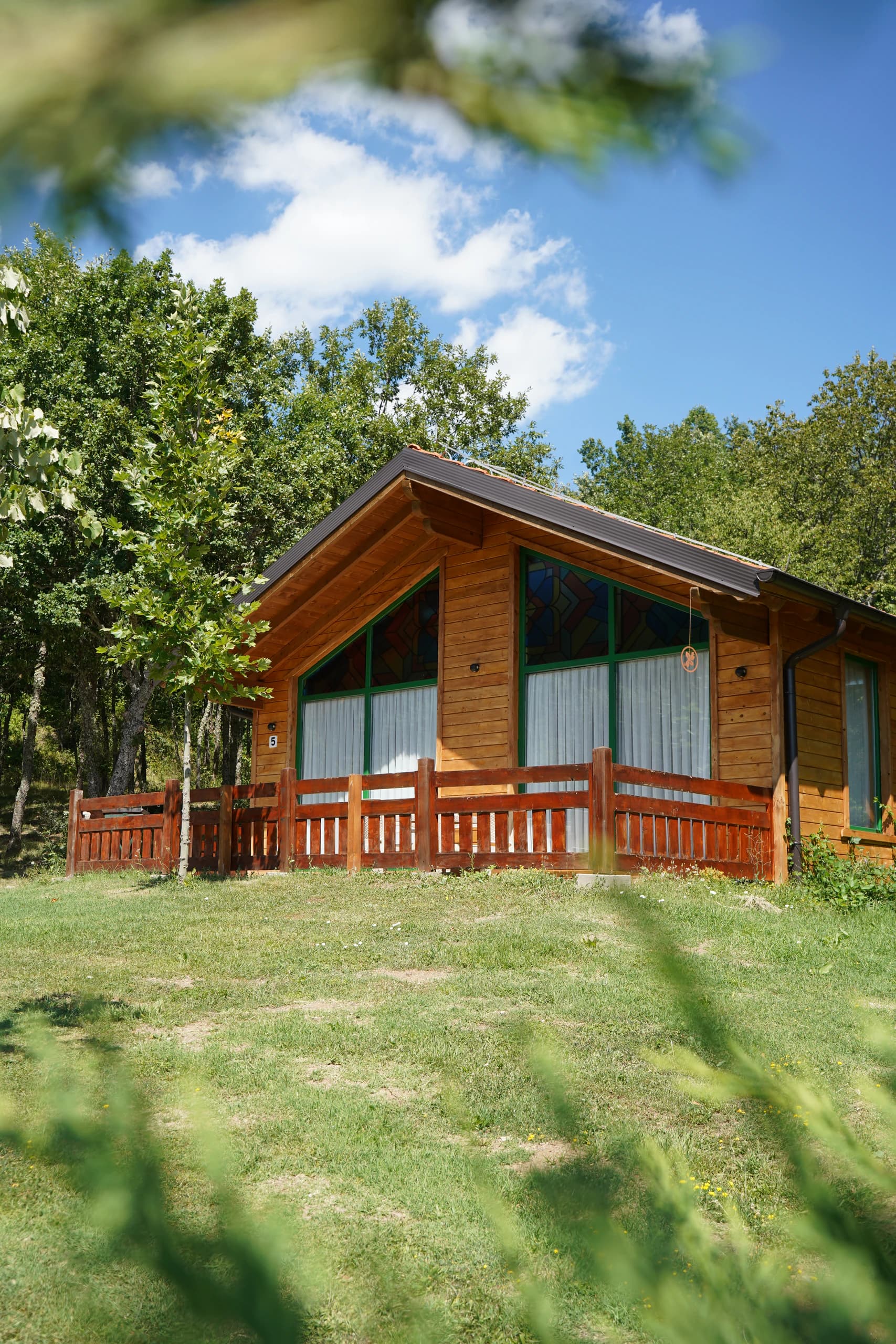 A timber chalet with its stained-glass gable, among the trees