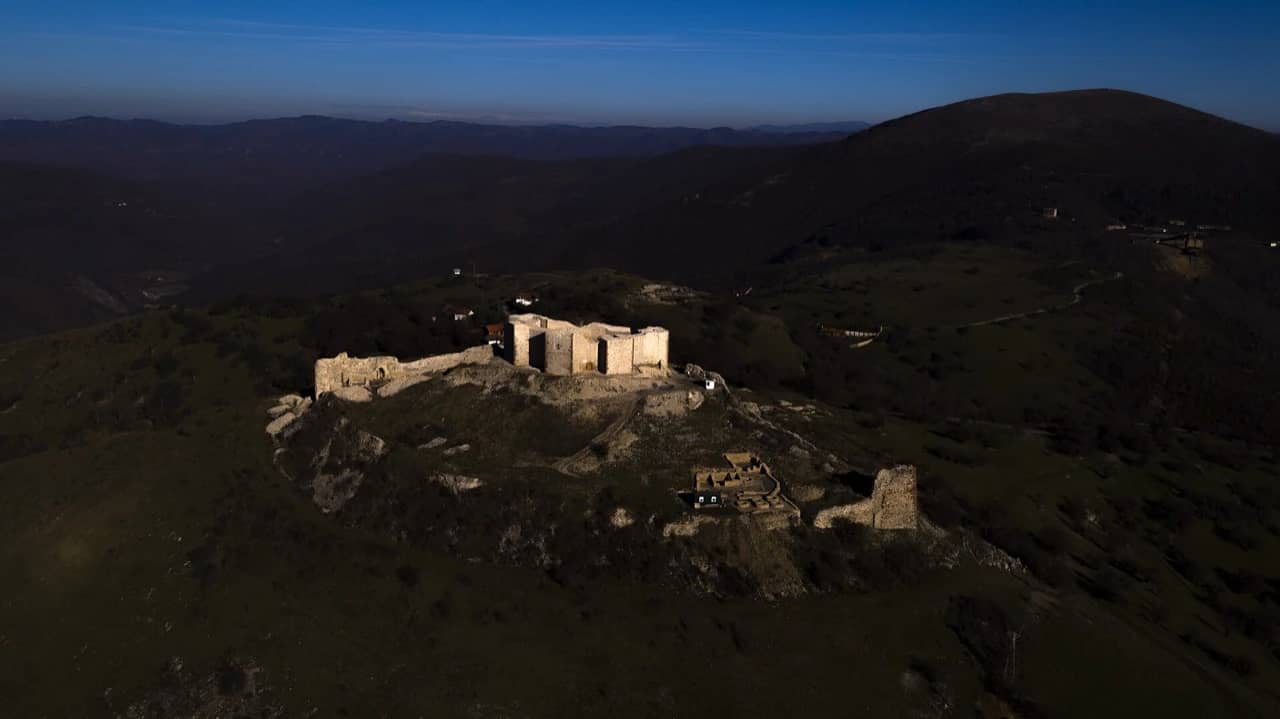 The Novobërdë fortress catching the last light on its ridge